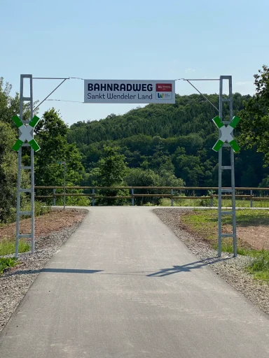 Einfahrt mit einem Schild, das den Namen des Standorts anzeigt, umgeben von Natur.