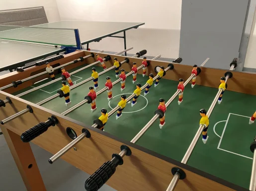 Tischfußballspiel mit Spielern in Rot und Gelb auf einem grünen Spielfeld.
