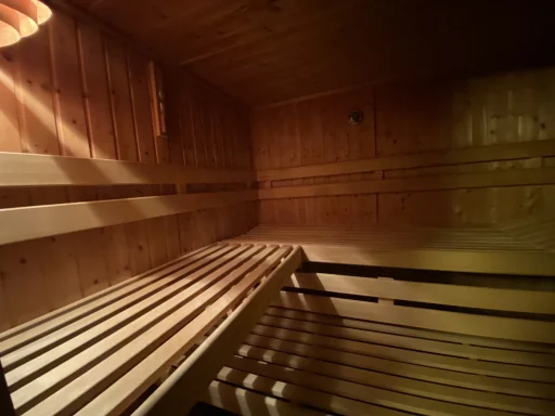 Innenansicht einer Holzsauna mit Sitzbänken und sanftem Licht.